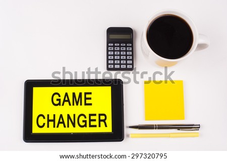 Business Term / Business Phrase on Tablet PC with a cup of coffee, Pens, Calculator, and yellow note pad on a White Background - Black Word(s) on a yellow background - Game Changer