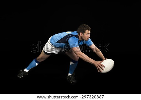 Rugby player  blue kit black background action passing ball studio