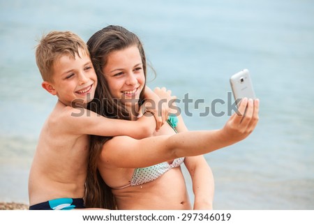 happy children with the smartphone on a beach