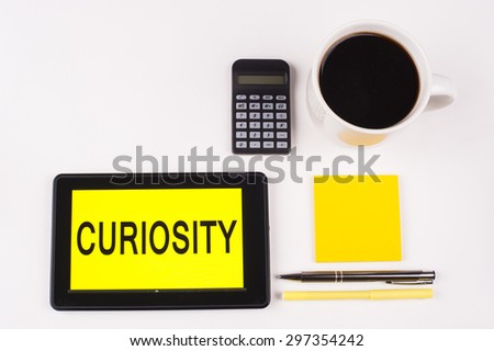 Business Term / Business Phrase on Tablet PC with a cup of coffee, Pens, Calculator, and yellow note pad on a White Background - Black Word(s) on a yellow background - Curiosity