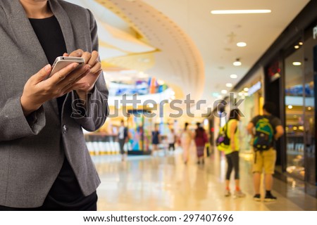 Women in shopping mall using mobile phone. Royalty-Free Stock Photo #297407696