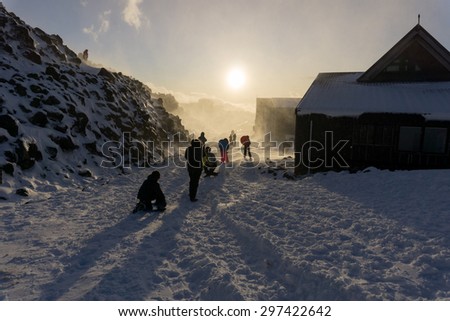 Unrecognisable people protect themselves and play backlit by fading sun in snow storm