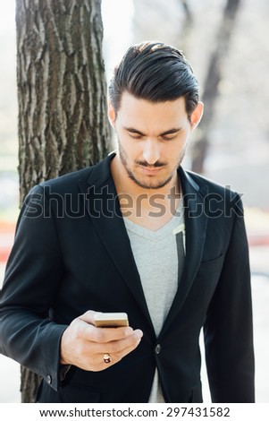 A young handsome italian boy walking through the city using a smartphone connected online- technology, social network concept