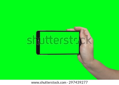 Hand holding mobile smart phone on green 