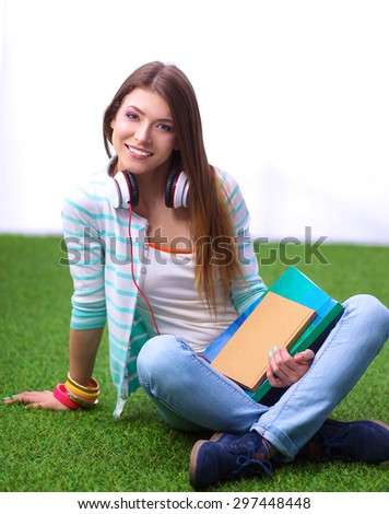 Woman reading book sits on the green grass.