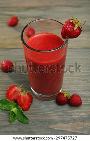 Glass of strawberry smoothie with berries on wooden table close up