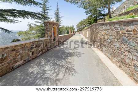 Fisheye view on vanishing path with stonemason fence ornated by mosaic icons. Kykkos Monastery, Cyprus.
