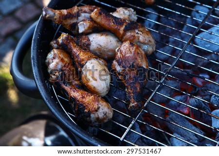 Many roasted hot fresh juicy chicken legs on grille cooking open air on fire with charcoal outdoor barbecue, horizontal picture