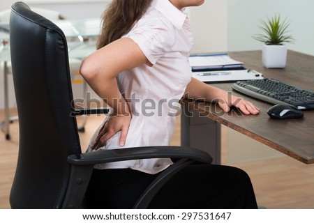Close-up Of Young Businesswoman On Chair Having Backpain In Office
