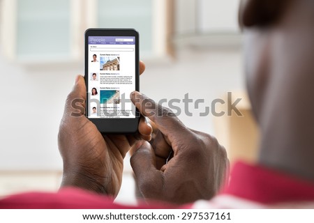 Close-up Of African Young Man Surfing On Social Networking Site Using Cellphone