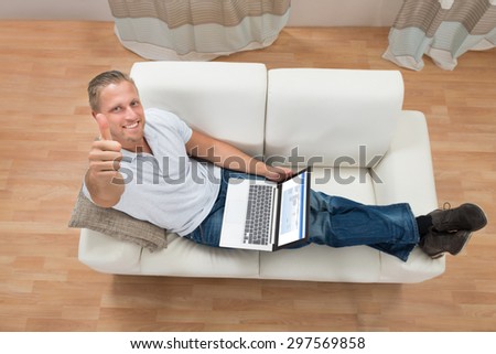 Young Happy Man Showing Thumb Up While Working On Laptop At Home