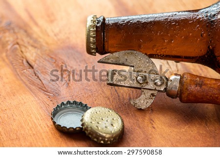 Vintage opener and beer over wooden surface