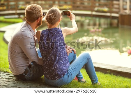 couple in love sitting in the park at sunset makes the selfie