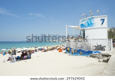 Beachgoers relax on the Beach next to graffiti adorned lifeguard tower number 7 at Arpoador