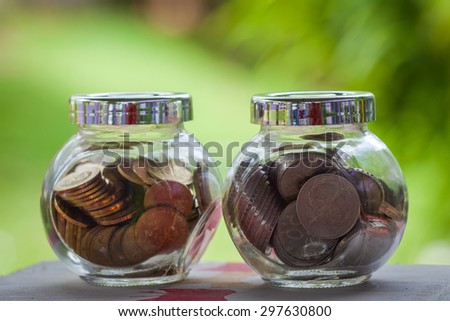 glass jar with coins with blurred background effects of plants in the background. bringing the concept and cost savings. appropriate financial purposes, savings, investment and banking.