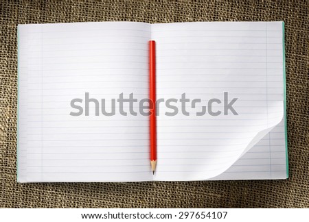 Notebook with red pencil on sack background