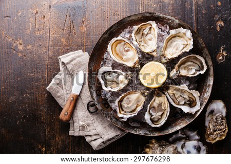 Opened Oysters on metal copper plate on dark wooden background Royalty-Free Stock Photo #297676298