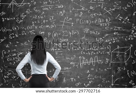 Rear view of a thoughtful woman who tries to solve math problems. Math calculations on black chalk board. Royalty-Free Stock Photo #297702716