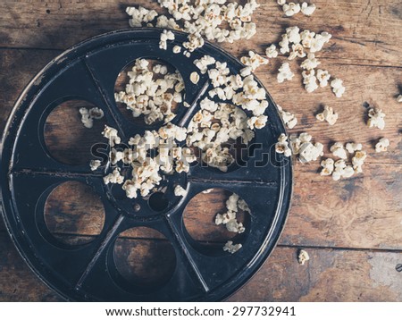 Cinema concept of vintage film reel with popcorn on wooden surface
