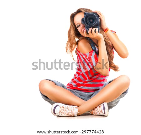 Photographer. Beauty Teenage Girl taking photo, sitting and Smiling. Beautiful Teen Girl with professional photo camera (unrecognizable). Isolated on a White Background. Teenager 