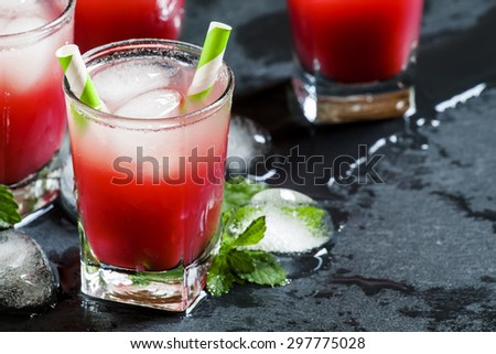 Cold red cocktail with ice and mint on a dark background, selective focus