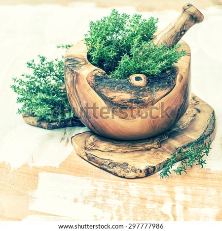 Mortar with fresh thyme herb. Olive wood kitchen tools. Healthy food ingredients. Vintage style toned picture