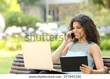 Entrepreneur working with multiple devices sitting in a bench in a park