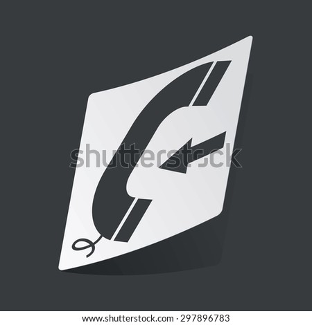 White sticker with black image of phone receiver and left arrow, on black background