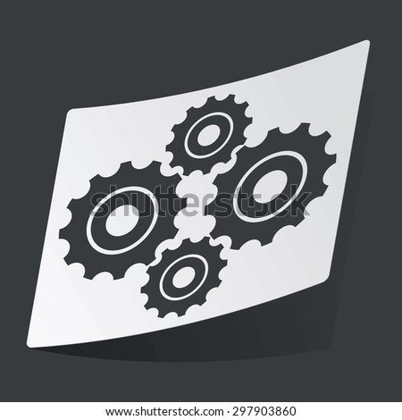 White sticker with black image of four cogs, on black background