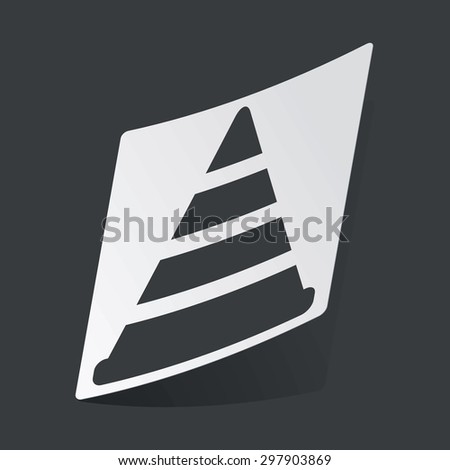 White sticker with black image of traffic cone, on black background