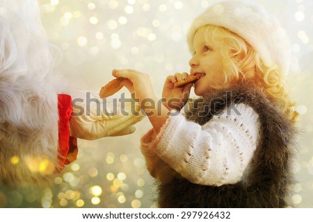 Little cute girl giving cookies to Santa Claus 