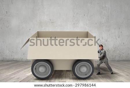 Young businessman pushing carton box on wheels