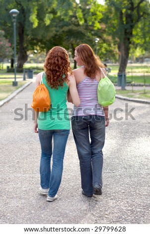 Two girlfriends going on avenue in park