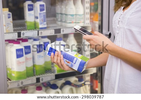 Woman taking picture of bottle of milk at supermarket