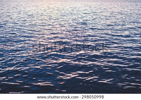 Sea waves and ripples colored pink and deep blue at sunset background no horizon seascape
