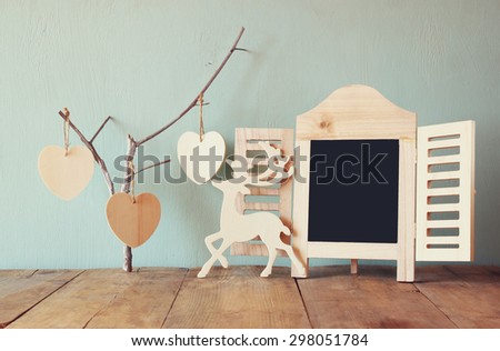 decorative chalkboard frame and wooden hanging hearts over wooden table. ready for text or mockup. retro filtered image 
