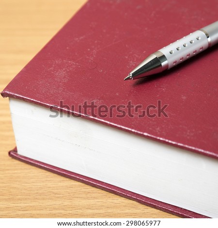 book and pen on wood background