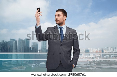 business, technology, internet and people concept - young businessman with smartphone over singapore city background
