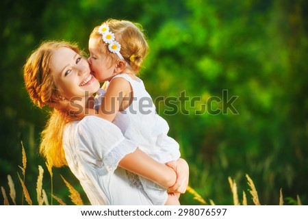 Happy family on a summer meadow. little girl child baby daughter hugging and kissing mother