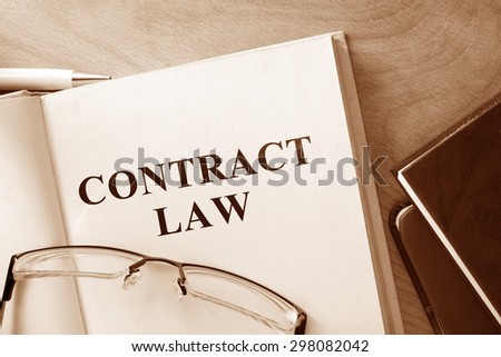 Book with words contract law and glasses.