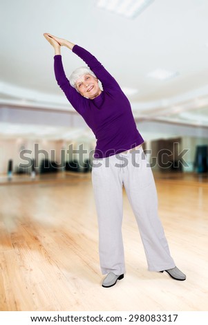 charming beautiful elderly woman doing exercises while working out playing sports in fitness training room
