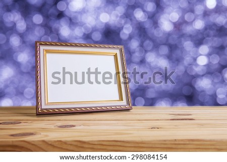 Vintage photo frame on wooden table over bokeh background
