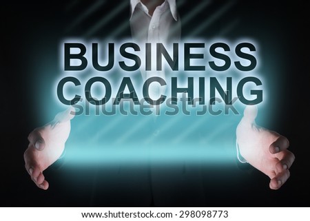 Glowing text "Business coaching" in the hands of a businessman. Business concept. Internet concept. Education concept.