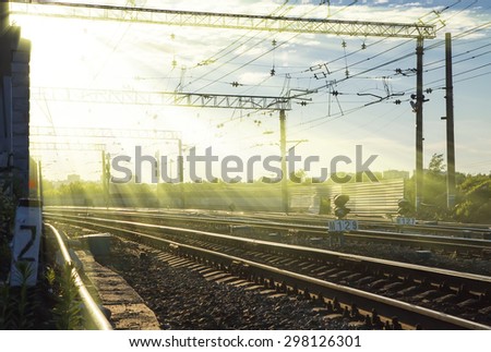 rays of the setting sun over railroad tracks in summer