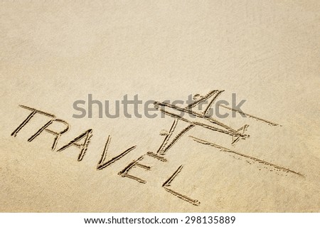 Drawing of an airplane and a word travel on sandy surface.