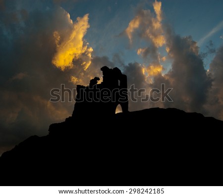 silhouette of the ruins of a medieval castle on a background of storm clouds
