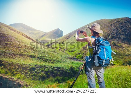 Woman hiker taking photo with smartphone at mountain. Backpacker photos landscape on the mobile phone.