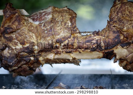 Large piece of fresh hot juicy delicious meat roasted on fire in smoke outdoor barbecue closeup, horizontal picture