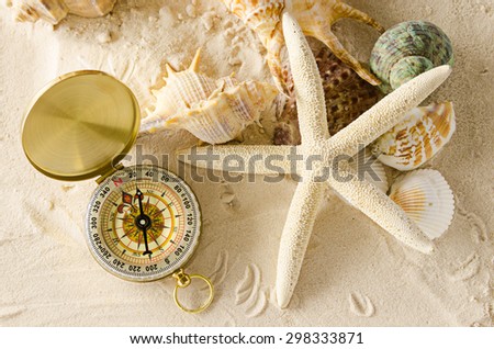 compass and sea shells on sand
