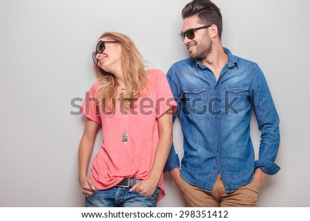 Happy young caouple laughing together while holding hands in pockets.